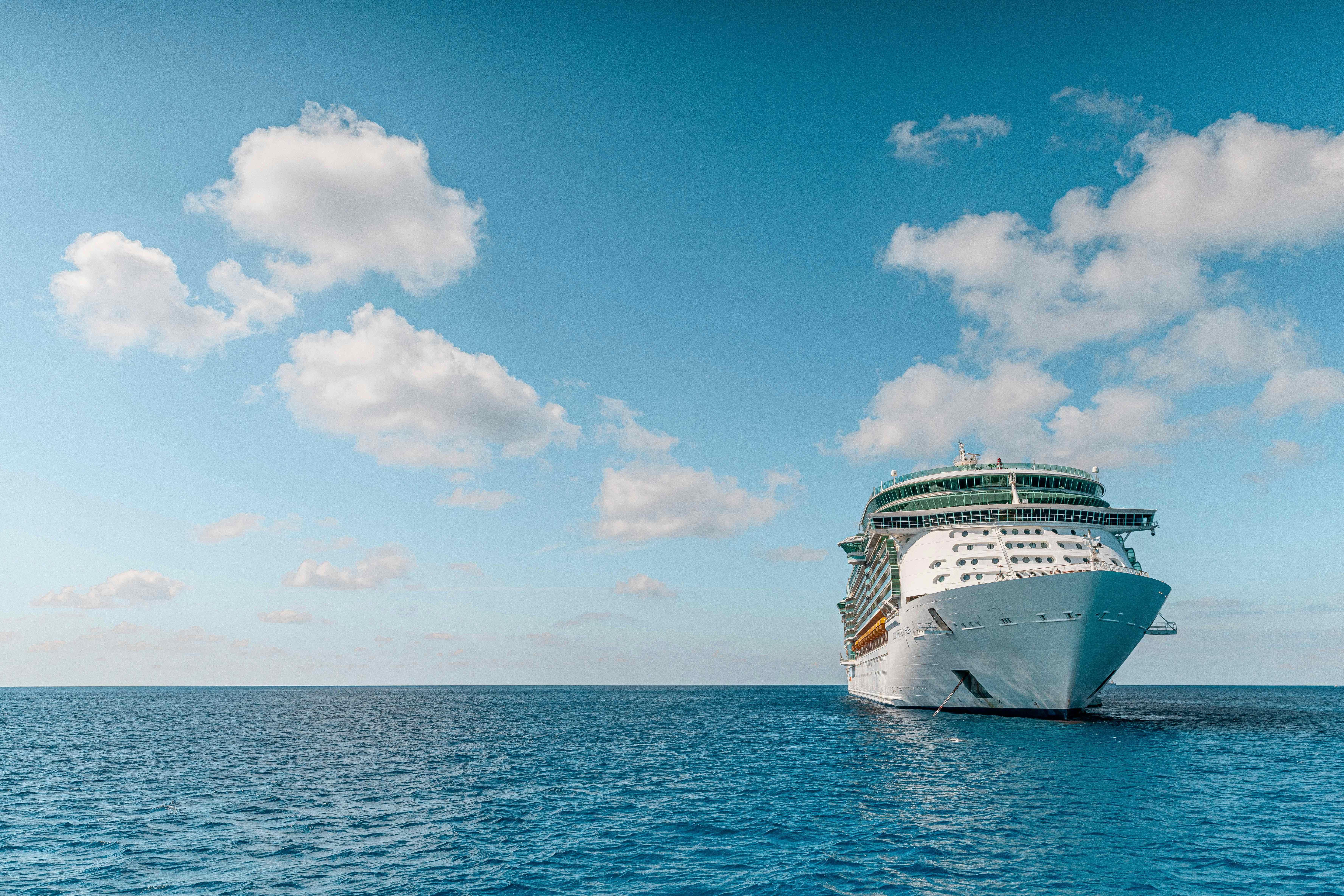Cruise ship sailing in the open ocean under a blue sky with clouds