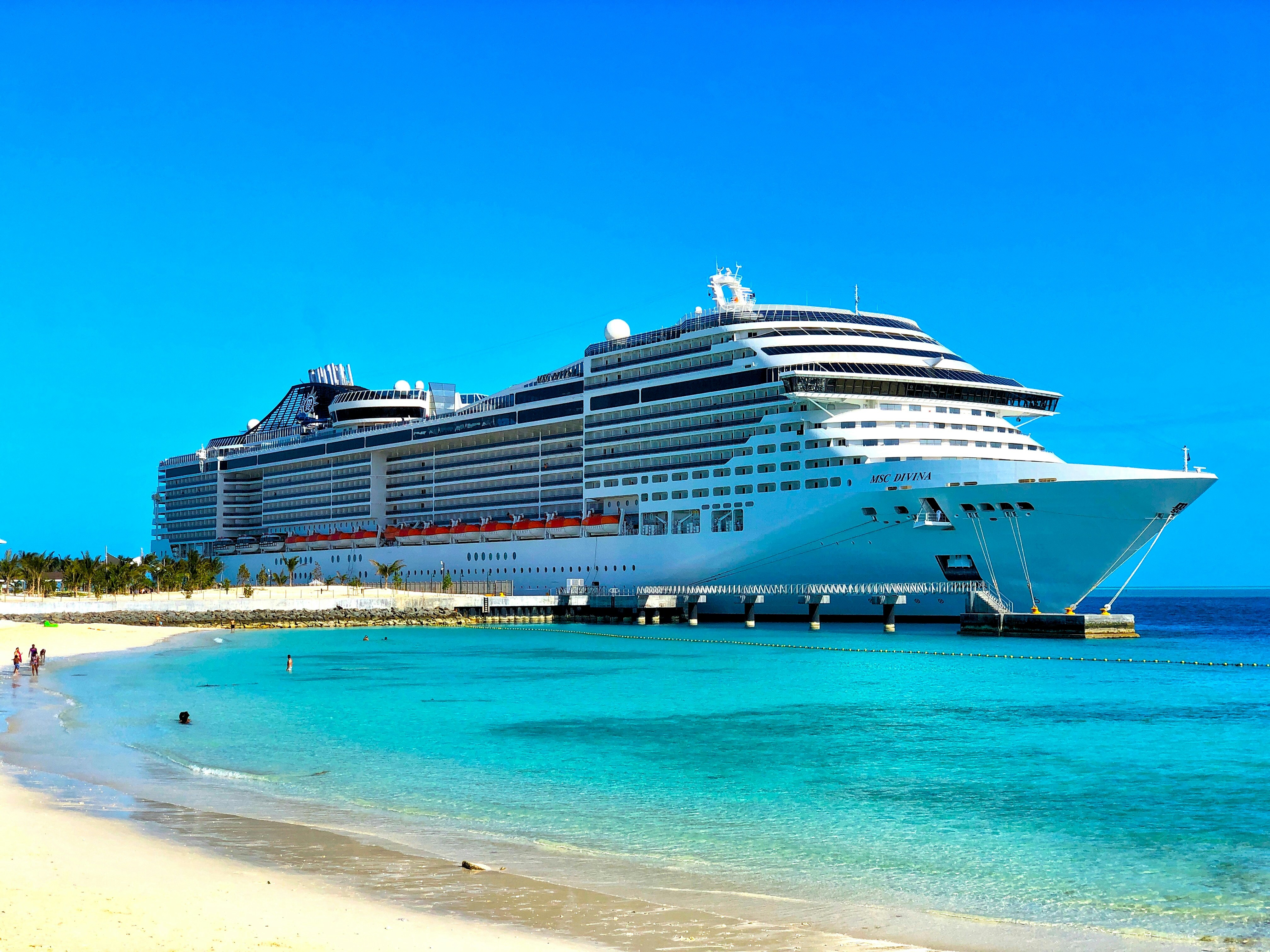MSC Divina cruise ship docked at a beautiful beach with turquoise waters
